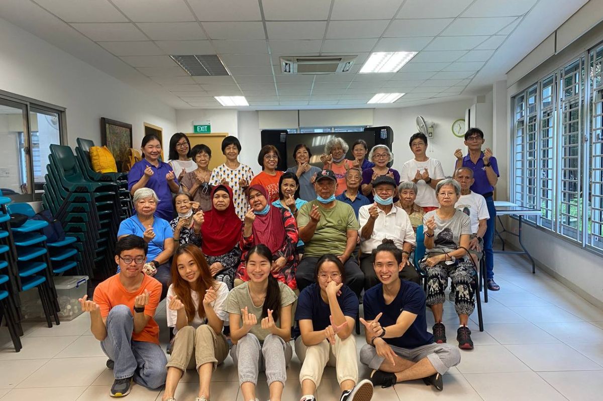 A group of student volunteers, Kho Yong Xiang, Jan Nicole Si Hui Ming, Kelyn Teo Yih Jia, Nicole Ng Kai Yi, Edrick Damario taking a photo with the elderly from Anglican Senior Centre (Woodlands) after their interactive dance session.