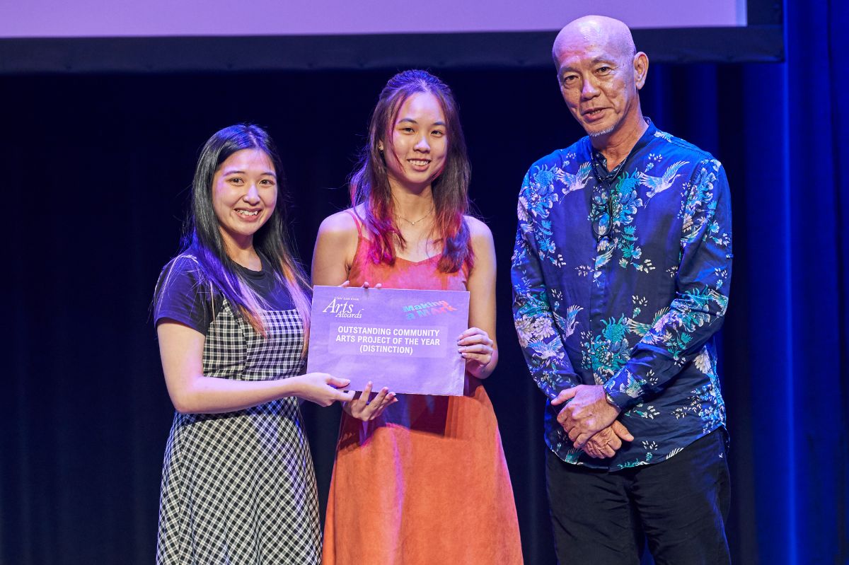 Leong Qian Ning (left) and Jan Nicole Si Hui Ming (right), Co-Heads of Community Outreach & Engagement AY22/23, receiving the Distinction Award for Outstanding Community Arts Project of the Year from Mr Seetow Cheng Fave, Deputy Director (Access, Wellness & Engagement) of Office of Student Affairs.