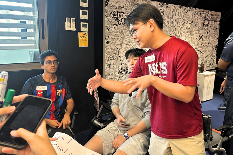 Zeng Zhi, NUS NPCC volunteer (standing), co-design care‑centred outreach with NUS hostelites. 