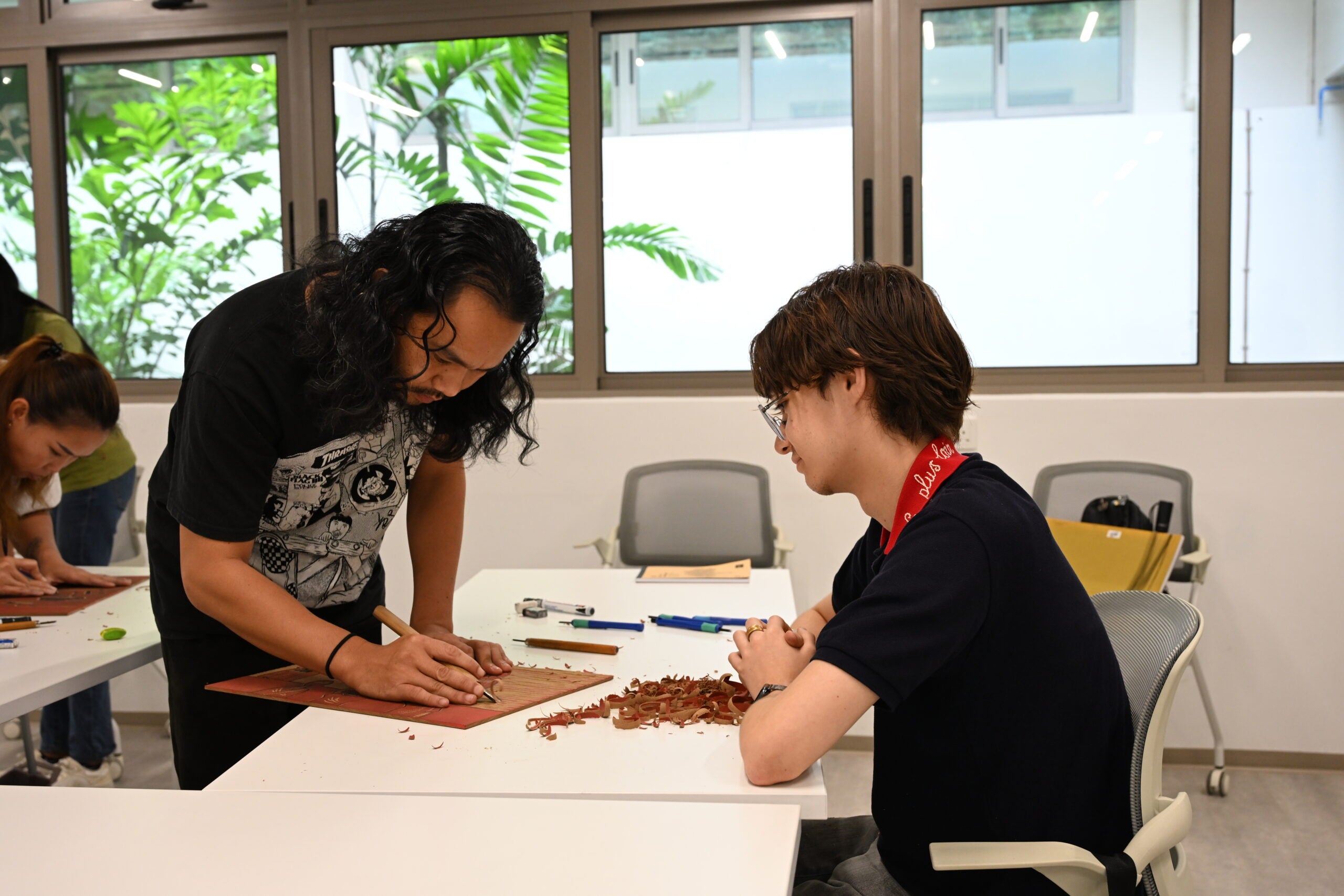 Mentor assisting students with carving techniques for their mural design.